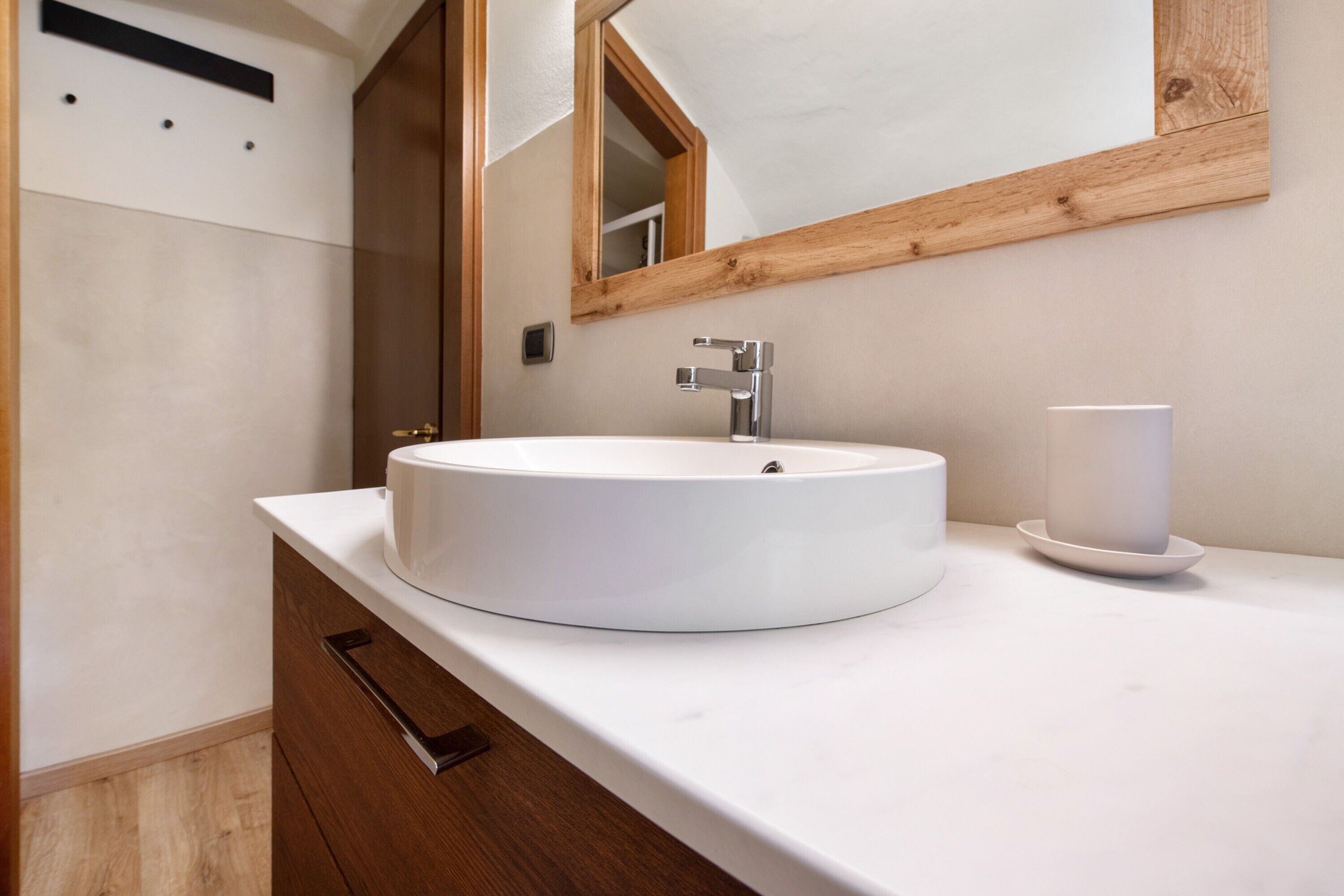Une salle de bain avec un lavabo blanc, un miroir et un meuble en bois.
