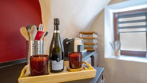 A tray with a bottle of wine, two glasses, and kitchen utensils on a counter.