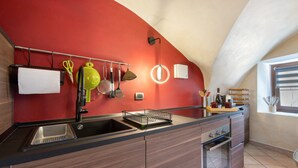 A modern kitchen with a red accent wall, a built-in oven, and a large island with a sink.