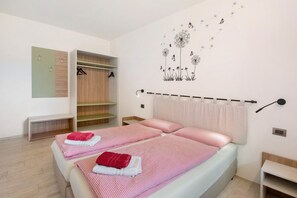 Une chambre avec deux lits, une armoire, un miroir et un élément décoratif mural.