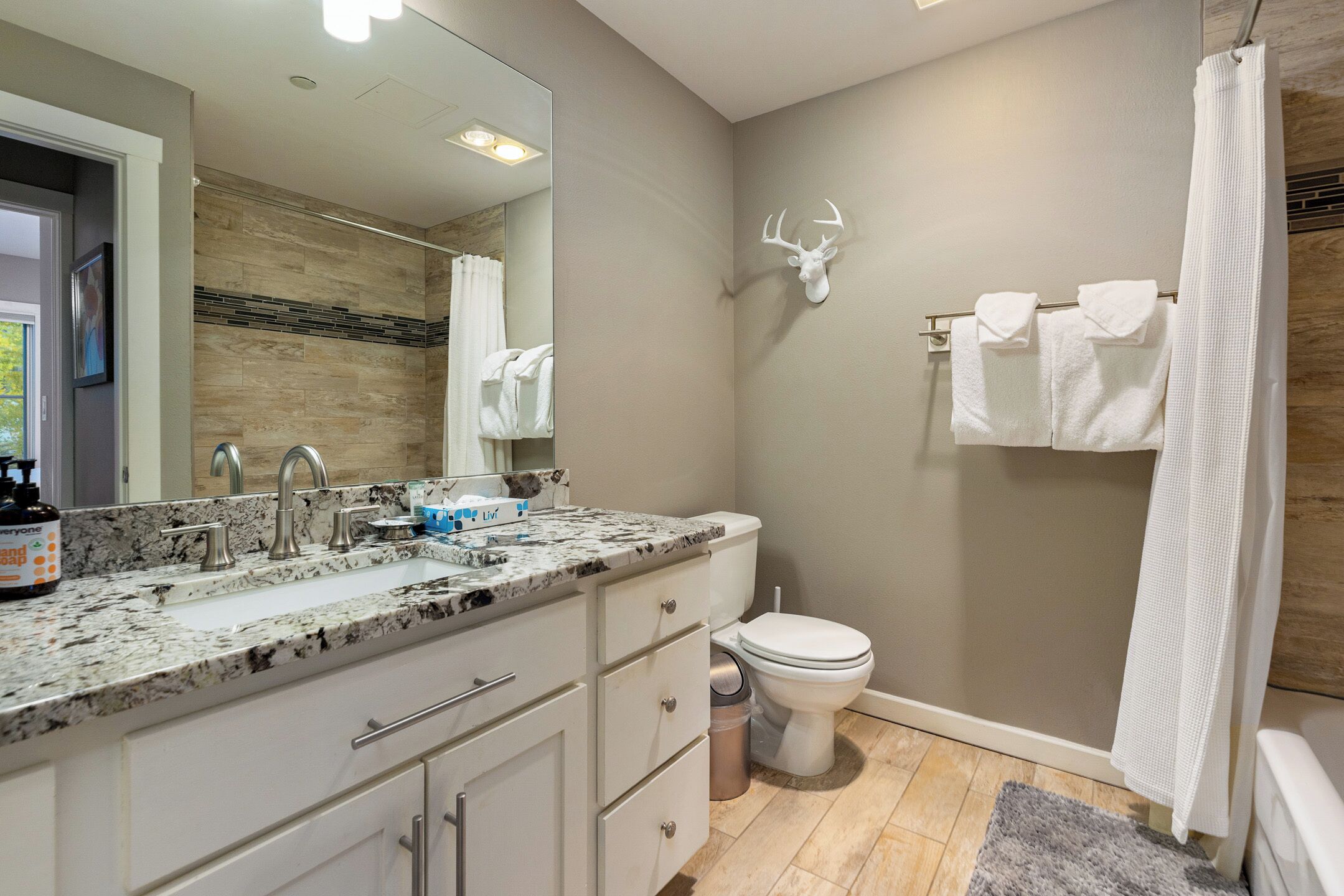 A bathroom with a marble sink, a toilet, and a shower curtain.