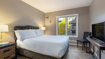 A modern bedroom with a large bed, bedside tables, a desk, and a TV.