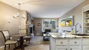 Een moderne keuken met een groot eiland, witte kasten en een eethoek met een ronde tafel en stoelen.