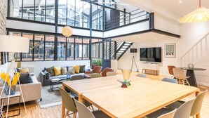 A spacious, modern interior with a large wooden dining table, comfortable seating, and a staircase connecting two levels. - Hedonist House - Fantastic Architect Loft for 10 guests near Metro (Paris)