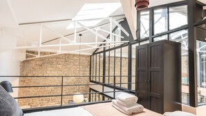 A bedroom with a skylight, a bed, a wardrobe, and a view of a stone wall. - Hedonist House - Fantastic Architect Loft for 10 guests near Metro (Paris)