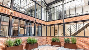 A modern atrium with brick walls, large windows, and metal furniture. - Hedonist House - Fantastic Architect Loft for 10 guests near Metro (Paris)