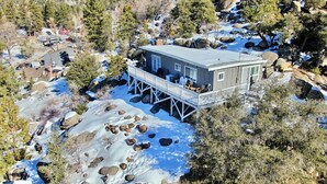 Une cabane dotée d’une terrasse, entourée d’un paysage enneigé et d’arbres.