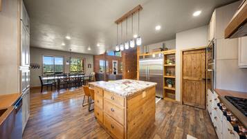 A spacious kitchen with wooden cabinetry, a central island, and a dining area with a view.