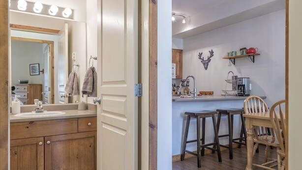 A modern bathroom with a wooden vanity, a large mirror, and a sink. - Pet friendly ground floor condo with mudroom directly slope side at Creekside (Silver Star Mountain)