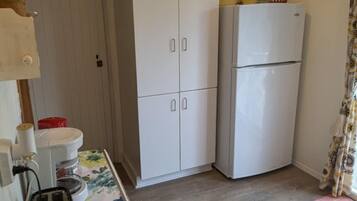 Una cocina pequeña con un refrigerador blanco, un armario de madera y un mantel estampado con motivos florales.