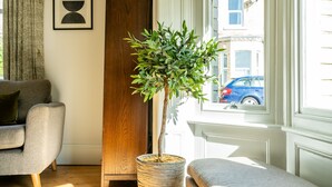 En stue med en potteplante, en sofa og et vindue med udsigt til gaden.