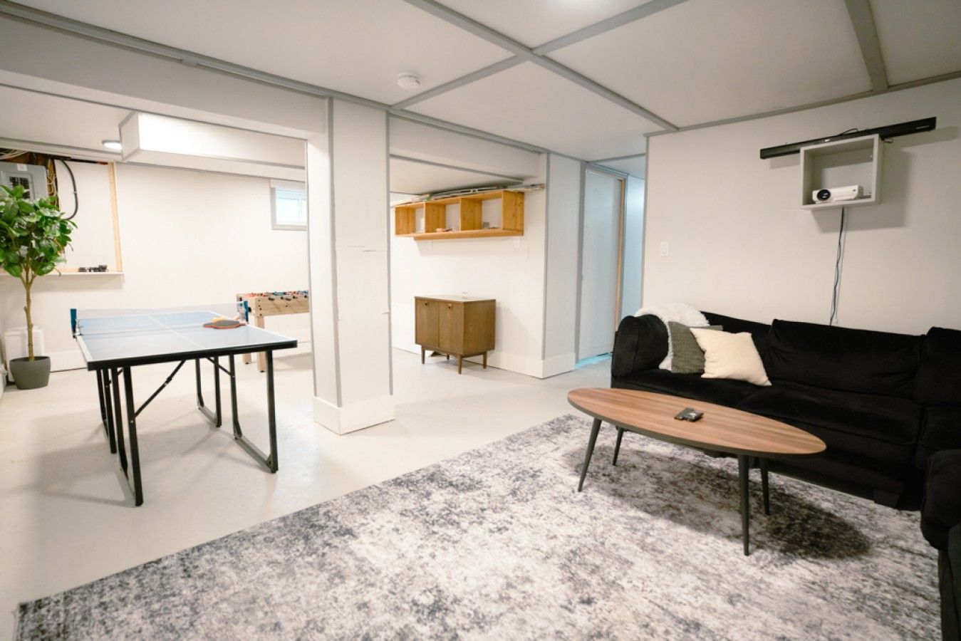 A modern living room with a ping pong table, a sofa, and a coffee table.