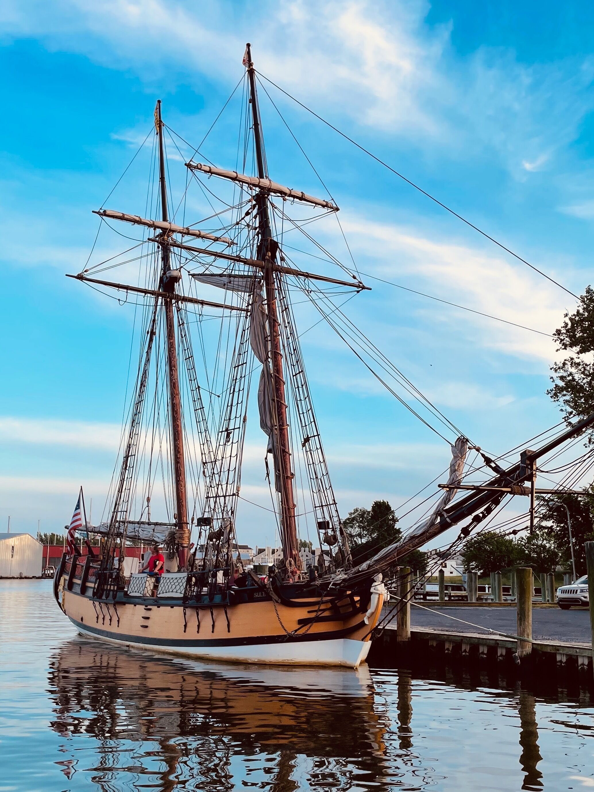 A tall ship docked at a pier with a clear sky.
