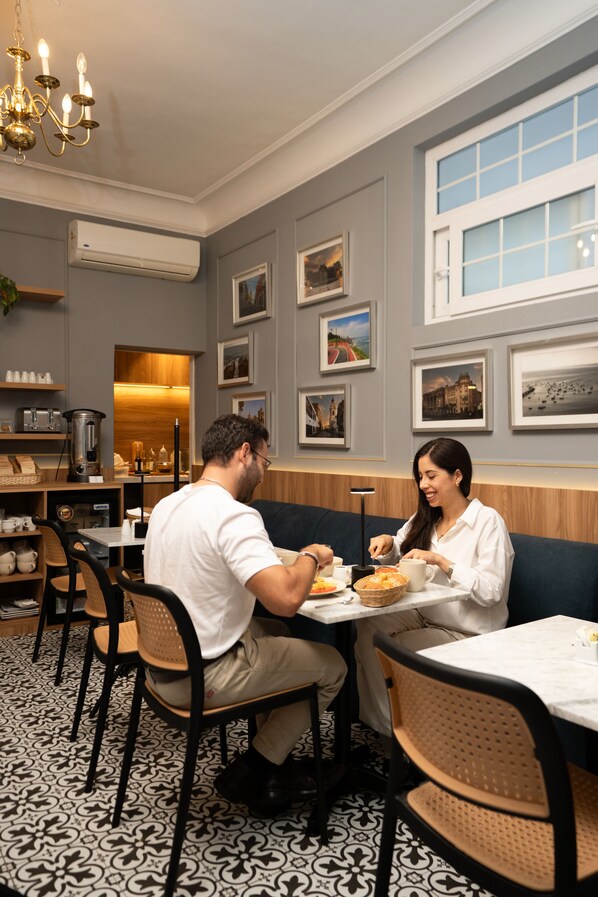 A restaurant with a dining area featuring tables, chairs, and a counter with a coffee machine. - Blu Hotel Boutique (Lima)