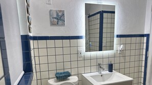 A bathroom with a toilet, sink, and mirror. - Beach Apartment in Hollywood  (Hollywood)