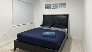 A bedroom with a bed, a headboard, a window with blinds, and wall art. - Beach Apartment in Hollywood  (Hollywood)