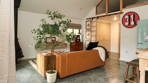 A cozy living room with a sofa, a potted tree, and a wooden cabinet.