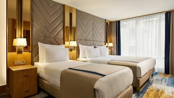 A hotel room with two beds, a wooden nightstand, and a large window with curtains.