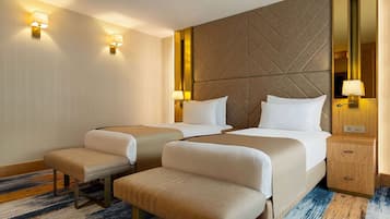 A hotel room with two beds, a large mirror, bedside lamps, a wooden nightstand, and a patterned rug.