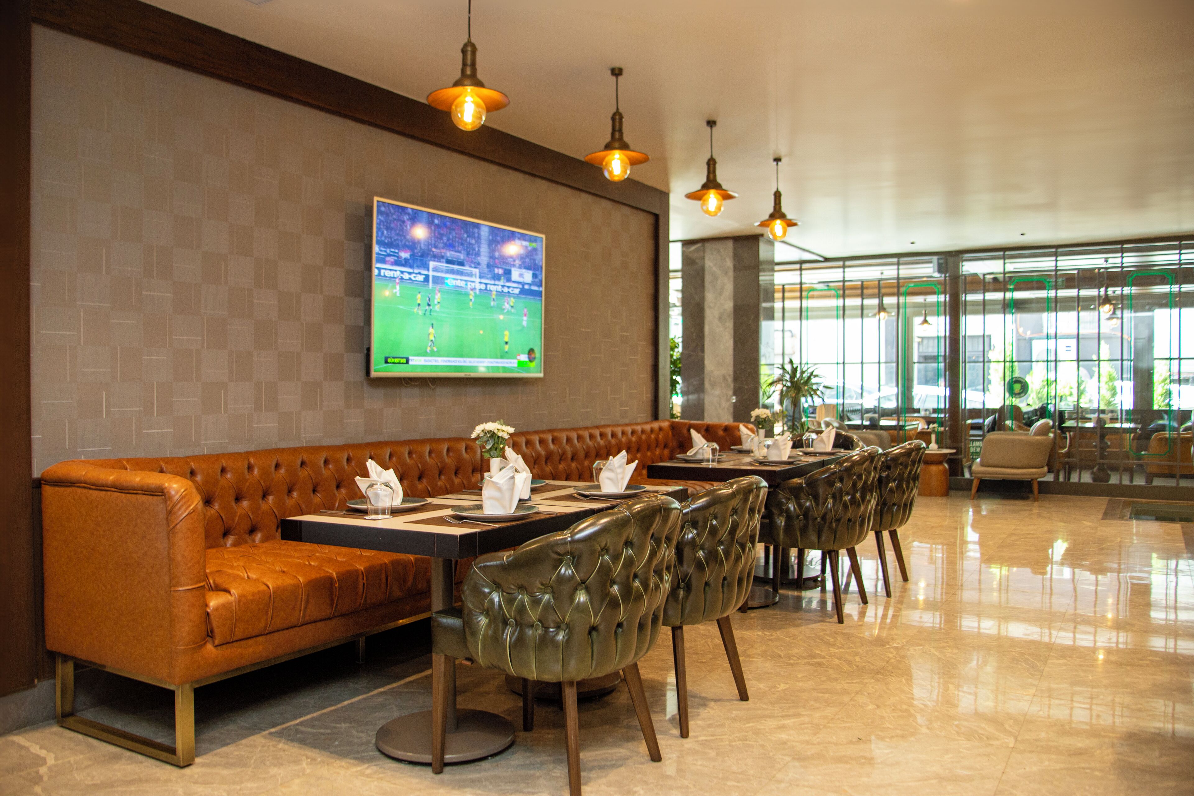 A modern restaurant with a leather sofa, dining tables, and chairs.