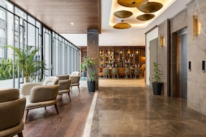 A modern lobby with leather chairs, a marble floor, a bookshelf, and a reception desk. - Days Inn By Wyndham Istanbul Bomonti (Istanbul)