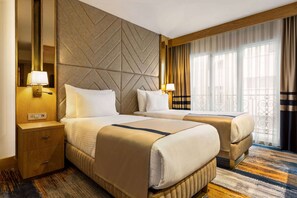 A hotel room with two beds, a wooden nightstand, a mirror, and a large window with curtains. - Days Inn By Wyndham Istanbul Bomonti (Istanbul)