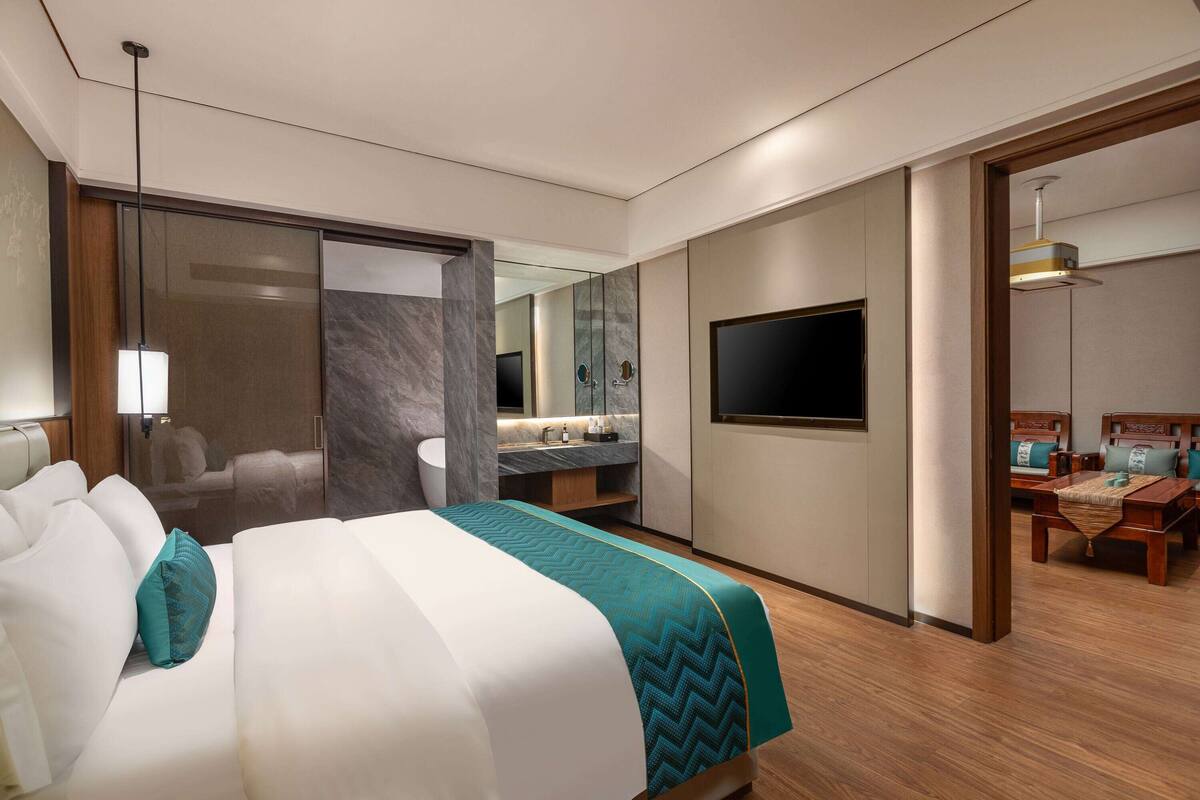 Una habitación de hotel moderna con una cama grande, televisor, escritorio y baño.
