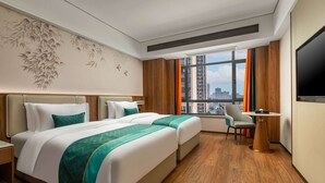 A hotel room with two beds, a desk, a chair, and a TV.