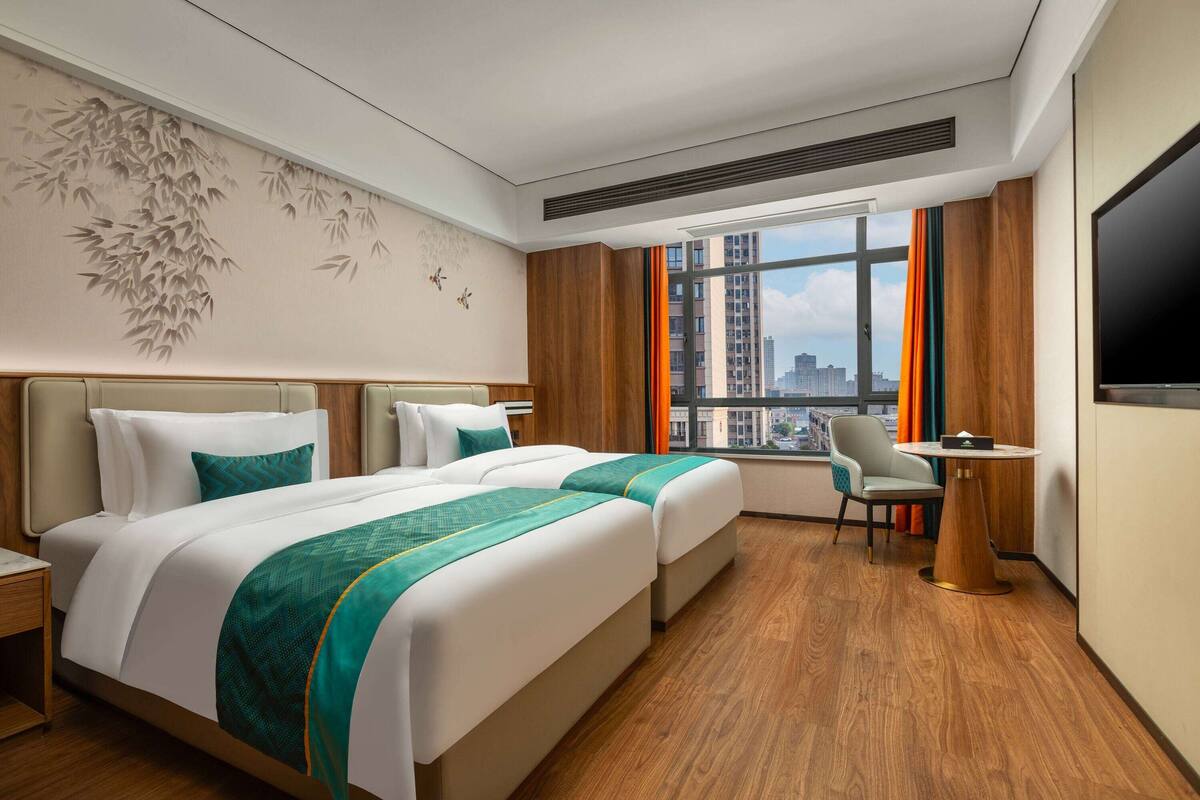 Una habitación de hotel con dos camas, un escritorio, una silla y un televisor.