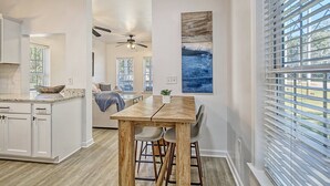 A modern kitchen with white cabinetry, a wooden dining table, and a ceiling fan. - Centrally located to Charleston’s best! (North Charleston)