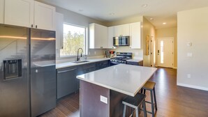 A modern kitchen with stainless steel appliances, white cabinetry, and a large island. - Ski-In/Ski-Out Granby Townhouse w/ Private Hot Tub (Granby)