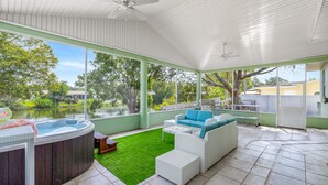 A covered outdoor area with a hot tub, white wicker furniture, and a view of a lake. - Lakeview Chic 3BD House for golf/beach lovers (Clearwater)