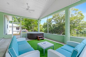 A covered outdoor area with a hot tub, seating, and a view of a lake. - Lakeview Chic 3BD House for golf/beach lovers (Clearwater)