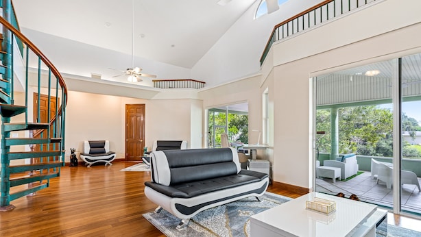 A spacious living area with a modern black and white sofa, a white coffee table, and a staircase with teal railings. - Lakeview Chic 3BD House for golf/beach lovers (Clearwater)