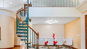 A spacious dining area with a high ceiling, a wooden staircase with teal railings, and a chandelier. - Lakeview Chic 3BD House for golf/beach lovers (Clearwater)