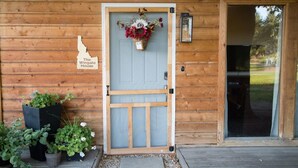 A wooden cabin with a blue door, a welcome sign, and a basket of flowers. - Wingate - Meridian, Cozy Acreage in the heart of the city (Meridian)
