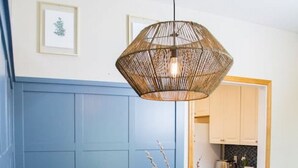 A dining area with a table, chairs, a hanging light fixture, and a kitchen in the background. - Wingate - Meridian, Cozy Acreage in the heart of the city (Meridian)