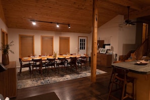 Un comedor con una mesa y sillas de madera, un tapete y una escalera que sube a un segundo piso.