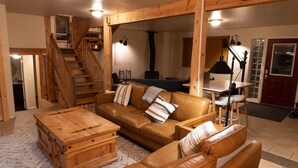 Un salon chaleureux avec un escalier en bois, un canapé en cuir et une table basse en bois.