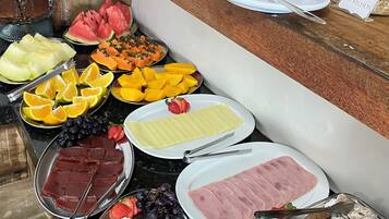 A buffet spread with various food items including fruits, cheeses, and meats.