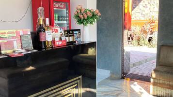 A reception area with a black counter, a Coca-Cola refrigerator, a floral arrangement, and a view of an outdoor patio.