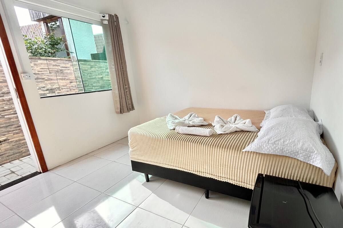 A bedroom with a bed, a window, and a door.