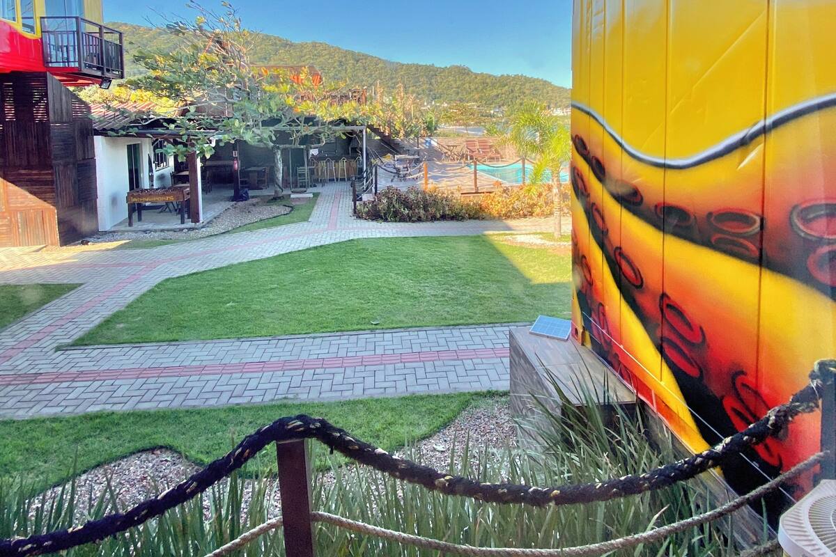 A view of a courtyard with a pathway, a building with a yellow exterior, and a mountain in the background.