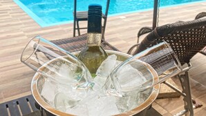 A poolside area with a pool, chairs, and a table with a bottle and glasses. - POUSADA SAO MIGUEL BEACH (Penha)