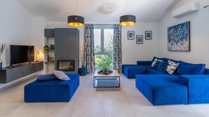 A modern living room with a TV, sofa, and fireplace. - Villa InSa (Pican)