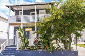 A two-story building with a balcony, steps leading to the entrance, and a sign indicating a car rental service. - The Dylan Suites 5- Comfortable Stay Near Downtown St. Augustine & Flagler (St. Augustine)
