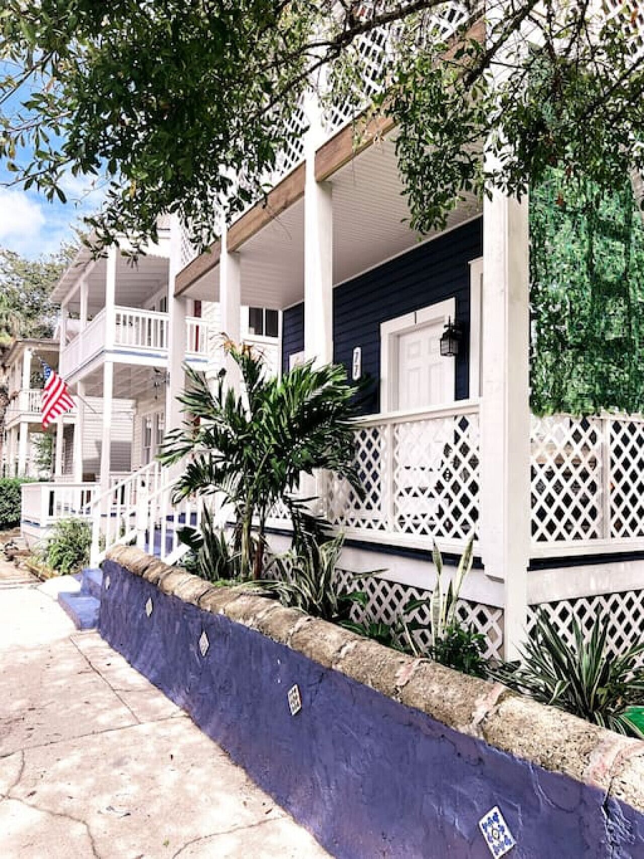 A multi-story building with a white exterior and a balcony on the second floor.