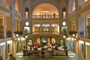 A multi-level atrium with a central staircase, multiple balconies, and a dining area with tables and chairs.