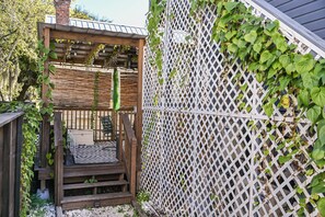 A wooden deck with a zebra-patterned rug, a white lattice fence, and greenery growing on it.