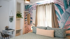 Un dormitorio con cama, escritorio, silla, planta colgante y ventilador de techo.